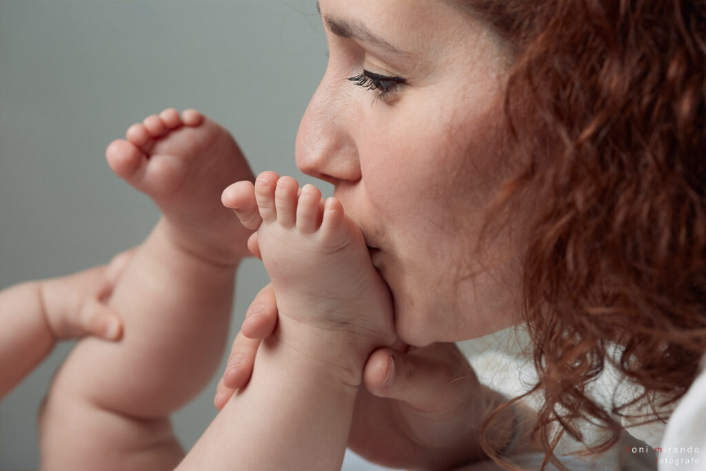 mama dando beso a pie de bebe en sesion estudio
